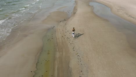 Vista-Aérea-Con-Una-Joven-De-Pelo-Largo-Montando-Una-Bicicleta-En-La-Playa-De-Arena,-Día-Soleado,-Playa-De-Arena-Blanca,-Concepto-De-Estilo-De-Vida-Activo,-Amplio-Disparo-De-Drones-De-Ojo-De-Pájaro-Avanzando,-Acercamiento-Lento