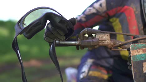 a motocross rider in slow motion holding his goggles and preparing for a race