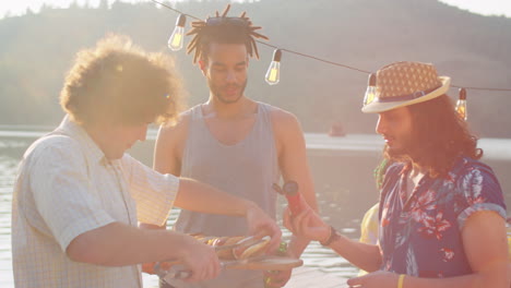 male friends preparing hot dogs on lake party