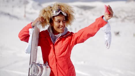 Mujer-Joven-Tomando-Su-Selfie-Con-Una-Tabla-De-Snowboard.