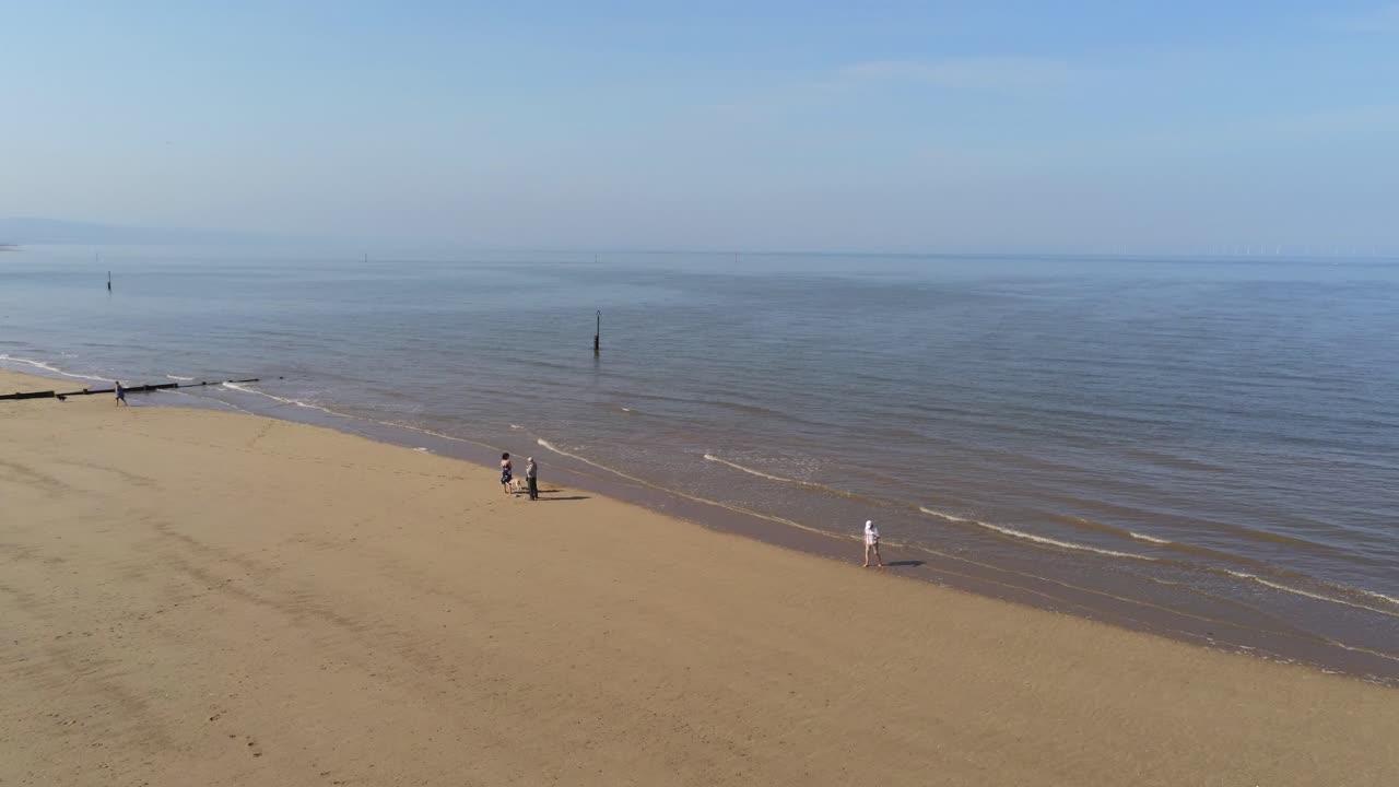 солнечный вид с воздуха на туристов на золотом песчаном пляже с панорамированием на морской пейзаж с приливом и отливом