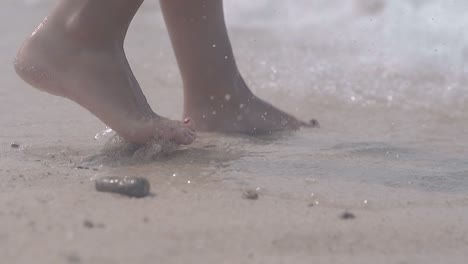 pasos de mujer en la playa húmeda entre las olas transparentes brillantes