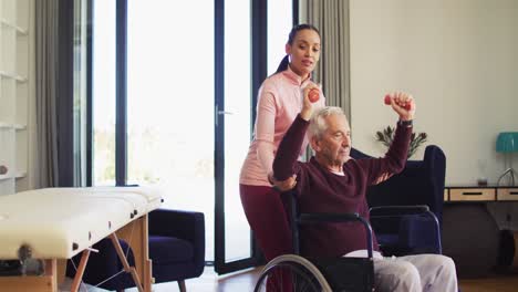 Video-of-happy-biracial-female-physiotherapist-exercising-with-caucasian-senior-man