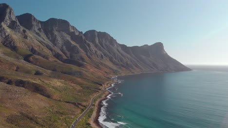 aerial drone view panning across mountain range, road and ocean