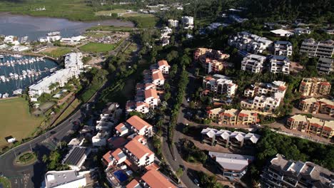 Vista-Aérea-Del-Complejo-De-Apartamentos-Airlie-Beach-Australia,-Edificios-En-La-Ladera-Sobre-El-Mar-Y-El-Puerto-Deportivo