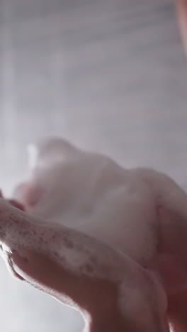 woman plays with foam in shower cabin closeup. playful lady blows heavy soap froth washing body in bathroom. having fun during bathing procedures