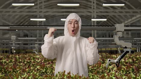 investigador hombre asiático gritando meta celebrando mientras estaba de pie en el invernadero con agricultores robóticos inteligentes