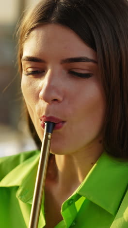 dark-haired beautiful young lady in green shirt smoking hookah. relaxing time with nargileh outdoors in summer. vertical video