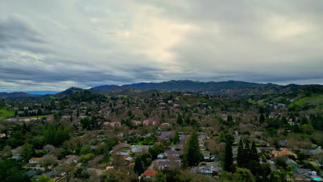 aerial view of a residential area nestled in hilly terrain with heavy clouds on the sky and horizon