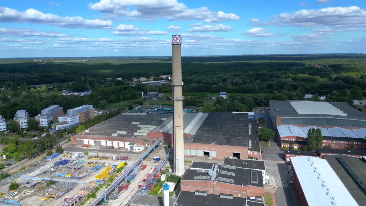 Hennigsdorf steel industry with industrial buildings, chimneys, storage area and a river in the background. Great aerial view flight