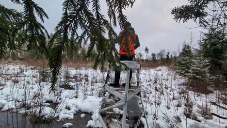hunter surveys the hunting area in winter, his rifle slung over his shoulder