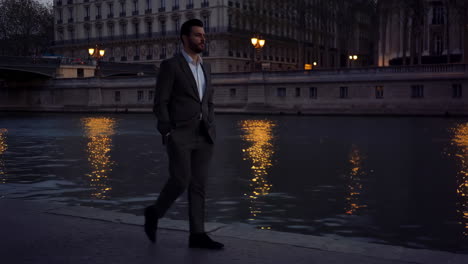 elegant man walking along city river at night