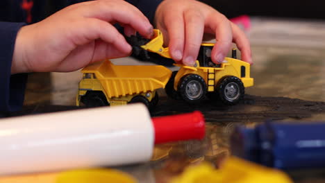 rack focus close-up of a child's hands playing with his tow digger and clay inside during lockdown