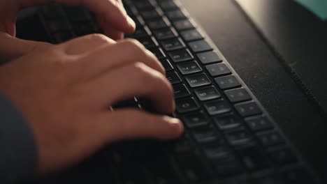 top-down-side-angle-of-fingers-typing-on-a-black-keyboard-back-lit