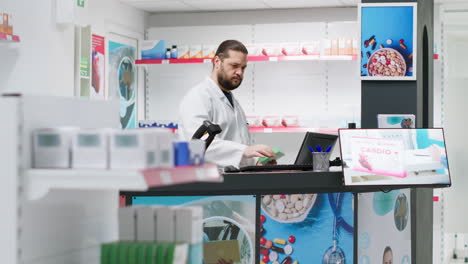 male pharmacist using scanner to register new stock at counter