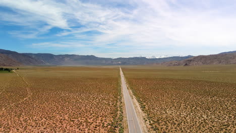 Hiperlapso-De-Nubes-Sobre-Un-Largo-Camino-Desértico-Con-Montañas-Nevadas