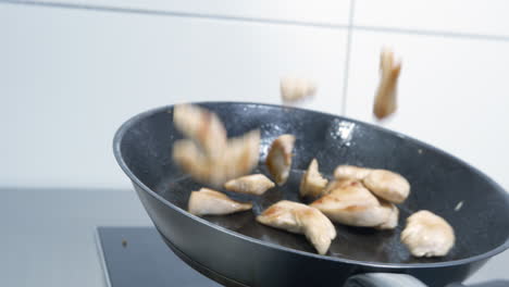 pieces of chicken are thrown up in a pan, turned over and shown