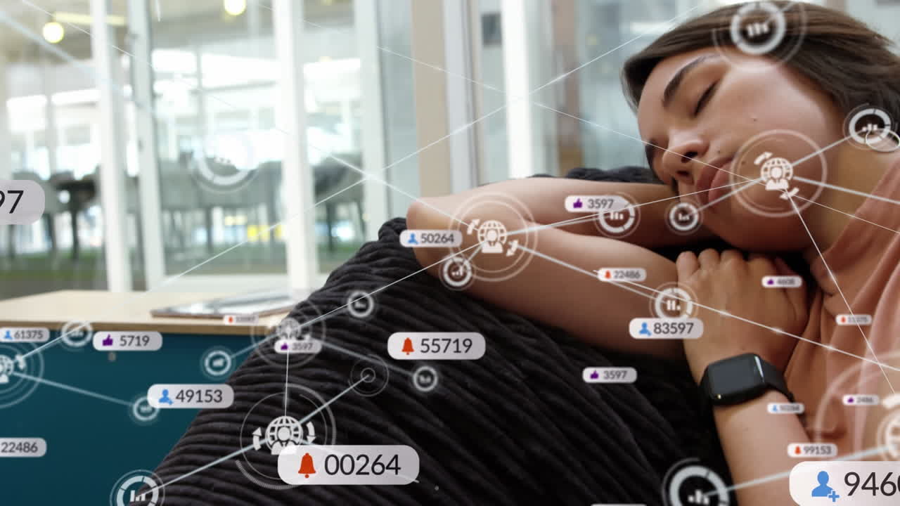 animación de iconos digitales y de redes sociales sobre una mujer biracial durmiendo en el sofá de la oficina