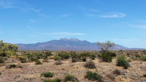 drone disparado hacia atrás sobre la pradera seca de arizona con los cuatro picos en el fondo