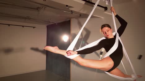 Young woman spinning in an aerial hammock in a studio