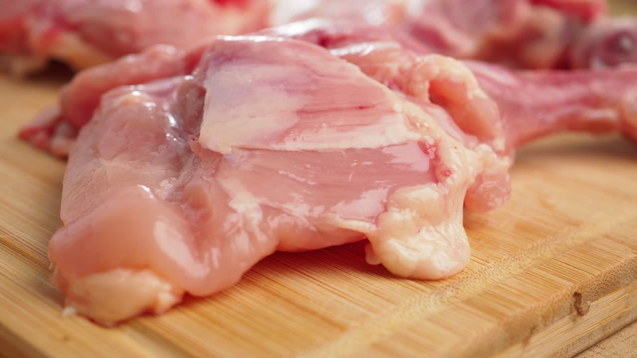 Pezzi di pollo crudo fresco su un tagliere di legno