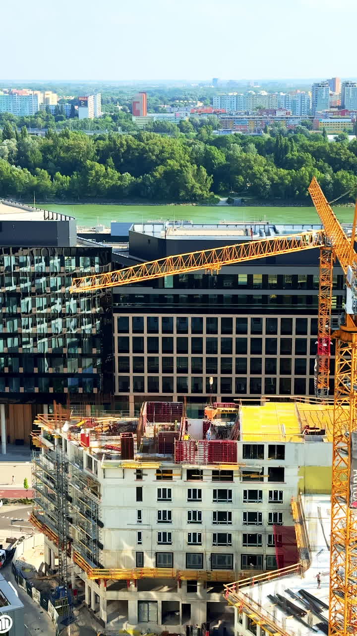 Waterfront construction project. Workers and machinery are busy at a construction site by a calm river, shaping modern buildings