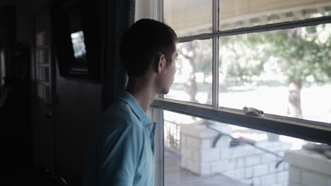 young man, teenage boy, watches out window