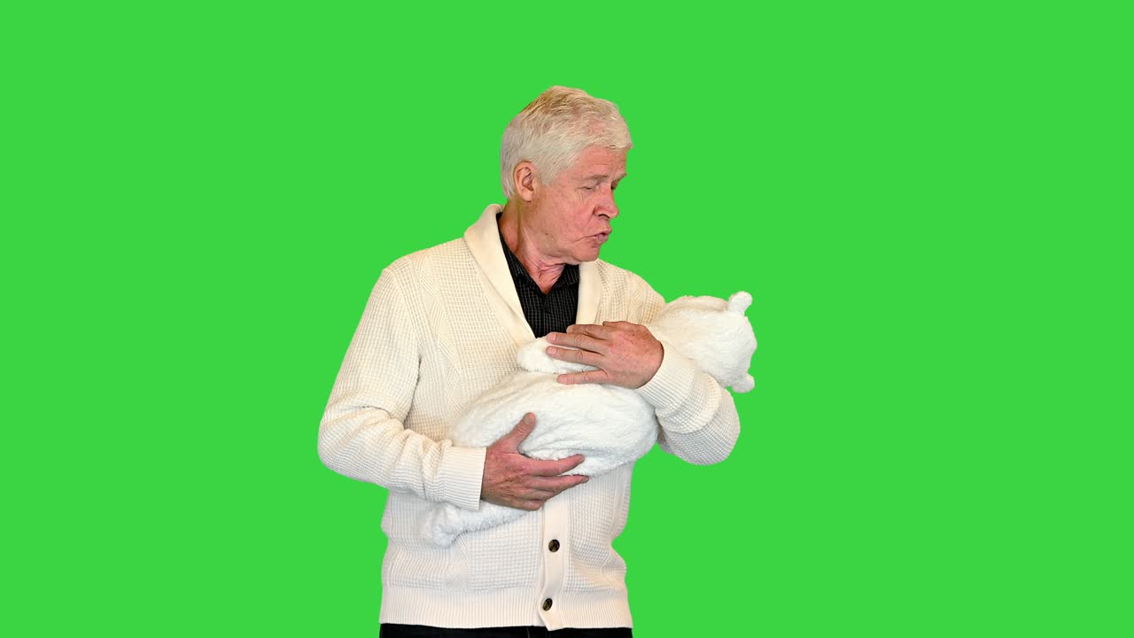 할아버지가 서서 손자를 초록색 스크린, 크로마 키에 들고 있습니다.