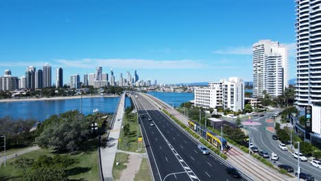 modern electric tram travelling over a bridge leading into a towering city skyline rising above a large body of water