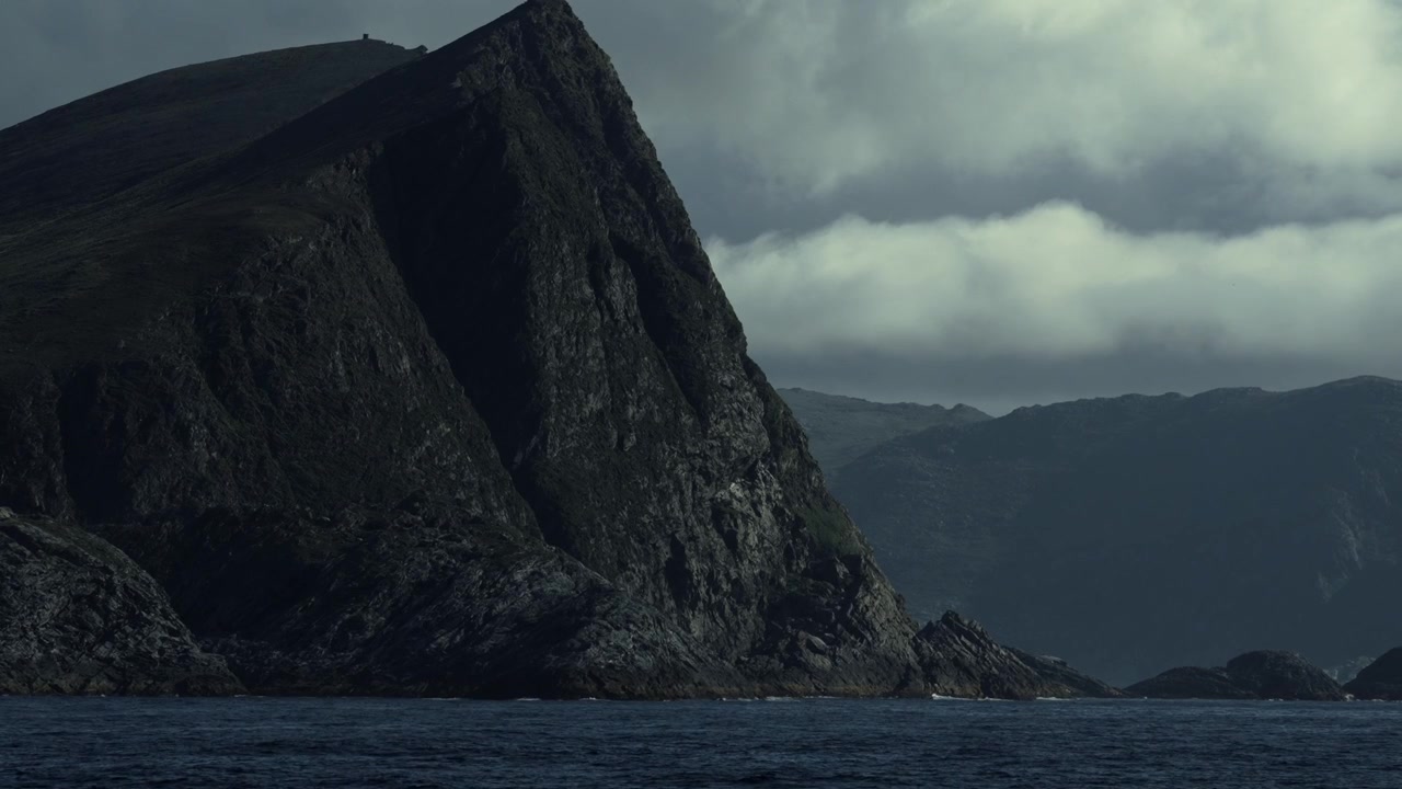 Rough Cliffs Rise From The Water Under Cloudy Skies In Norway Coast