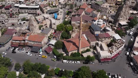 aerial orbit around tower at edge of road with homes surrounding stone formations, cappadocia turkey