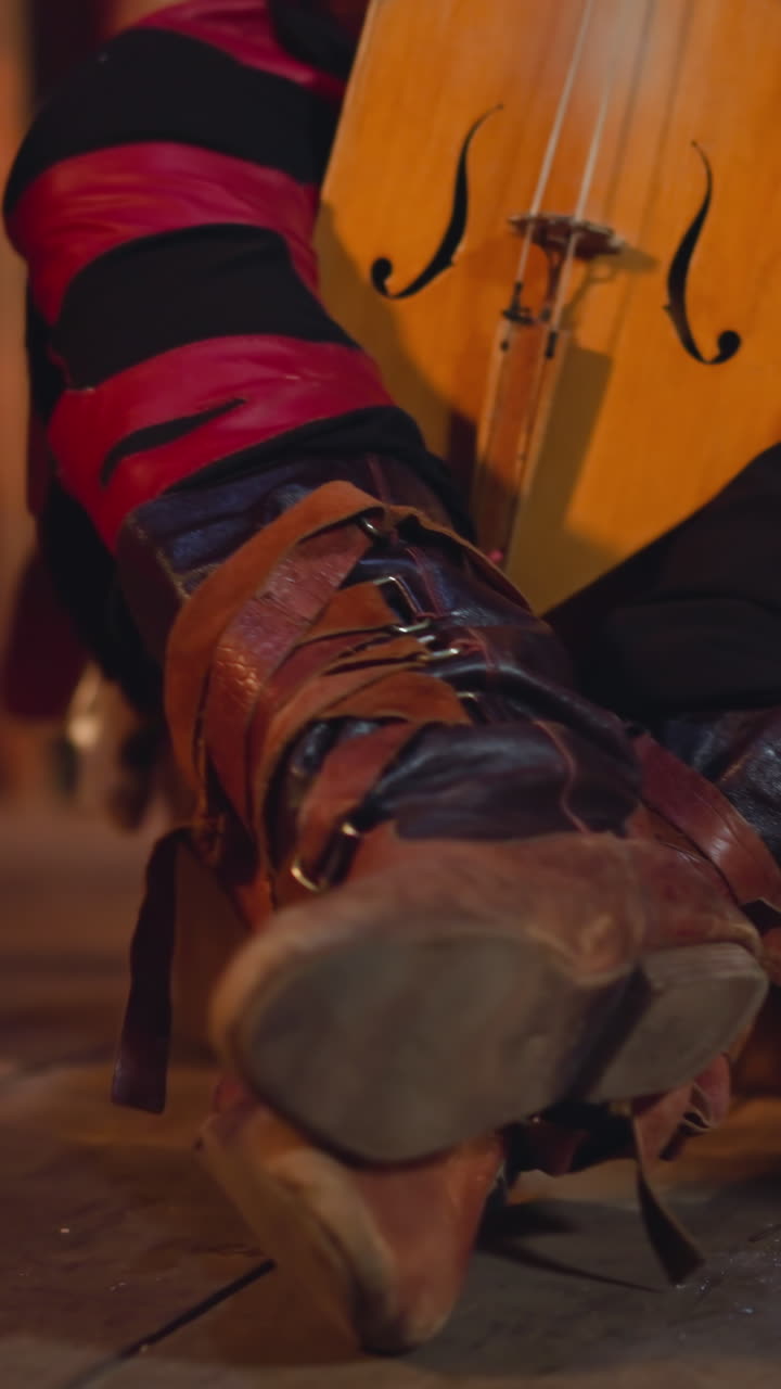 Musician in leather laced boots prepares to play igil with bow at ethnic concert on stage closeup. Siberian musical instruments. Culture and art