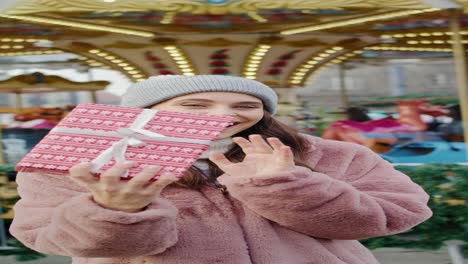 video of woman with christmas present and carousel in background