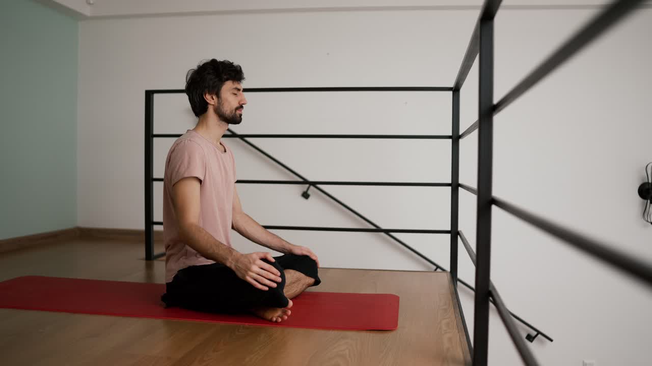 vista lateral de un hombre meditando en casa con los ojos cerrados sentado en un tapete de yoga