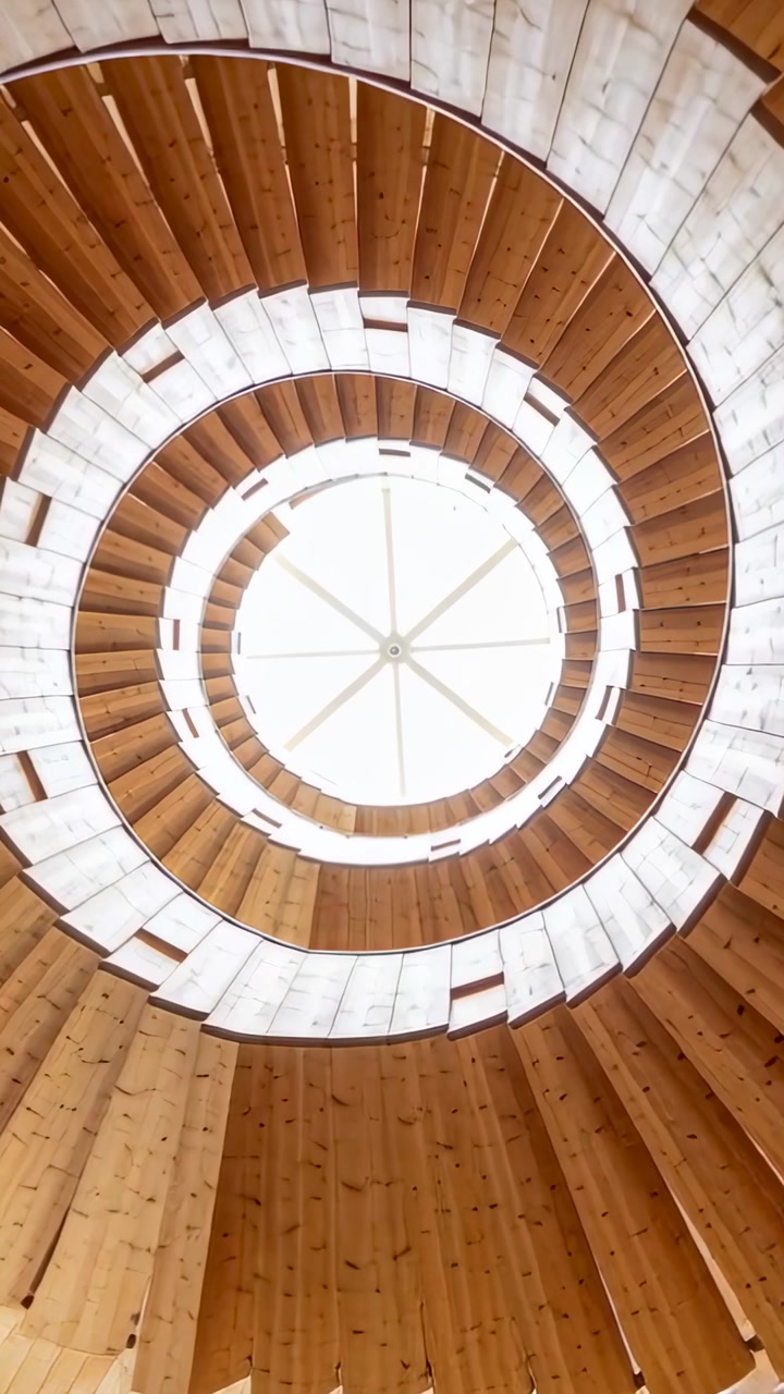 Vertical video: Tilting camera showing wooden spiral stairs inside tower, centering skylight