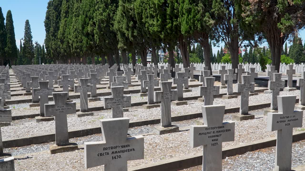 Gravestones of Serbian soldiers stretch in uniform rows at Zeitenlik military cemetery in Thessaloniki, honoring those who perished during World War I among cypress trees and solemn surroundings
