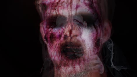 Close-up-of-sinister-man-with-horrible-scary-Halloween-zombie-make-up-blood-flows-and-drips-on-face