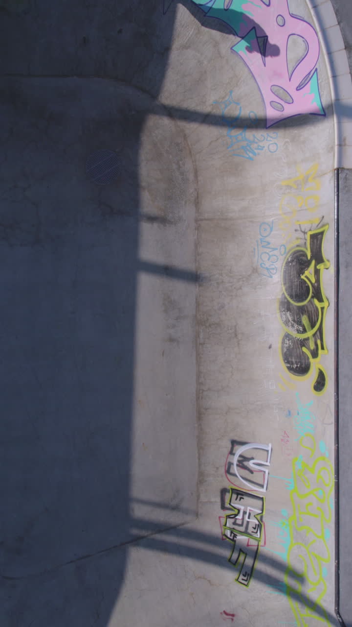 Surfskate Skateboarder riding in a large skate pool - Top down view, hiding and revealing between shadows - using Carver model - Vertical video
