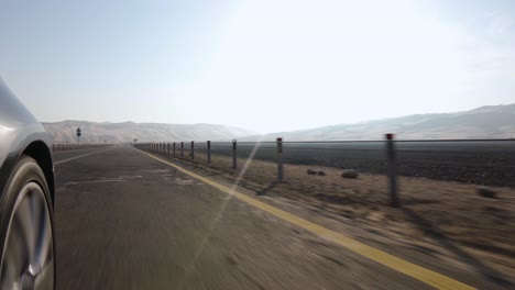 close-up of a car wheel with camera side mounted driving towards beautiful abu dhabi desert
