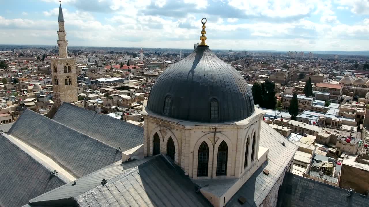 vista aérea sobre la mezquita de los umayyad en siria. un avión no tripulado está volando sobre la mesquita con la ciudad de damasco en el fondo.