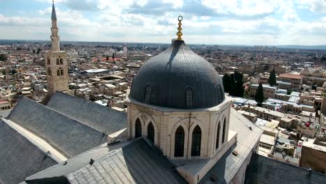 aerial view over the umayyad mosque in syria. drone is flying over the mosque with the city of damascus in the background.