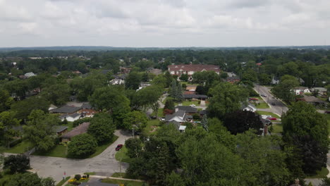 aerial ascend pedestal tilt down above suburban neighborhood, lush trees and yards