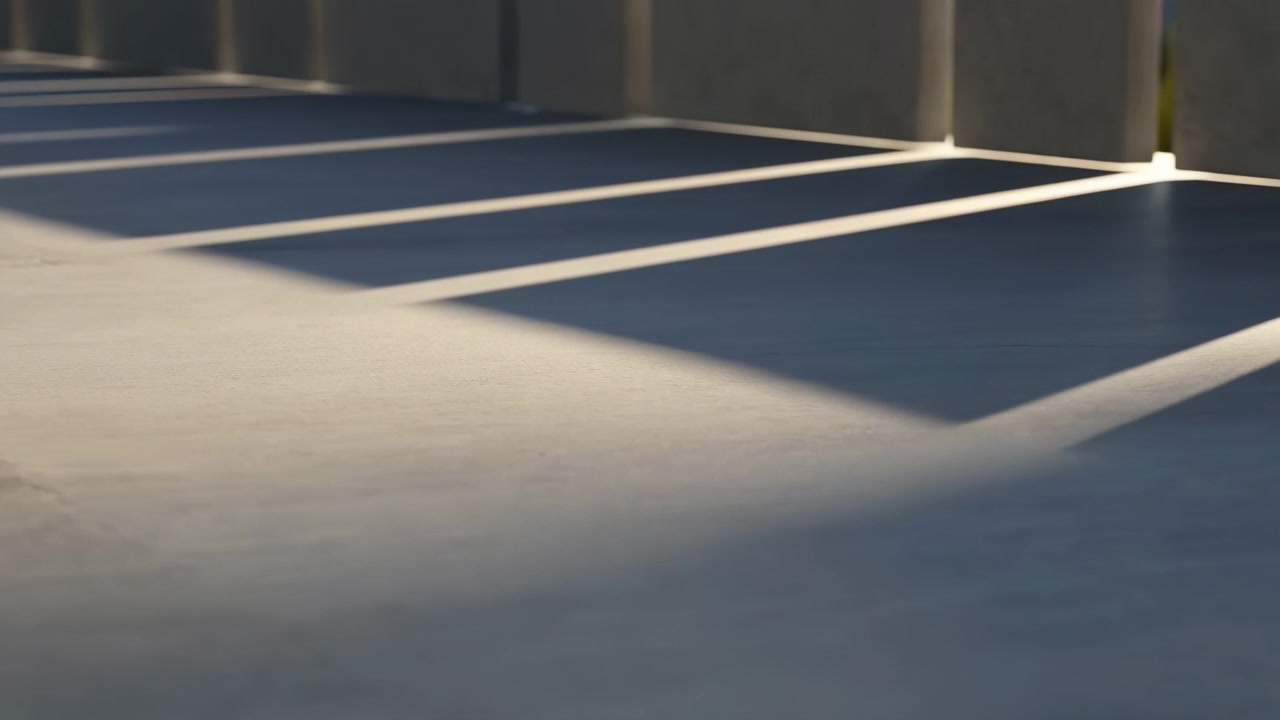 Low-ground motion view of empty parking bays where bright side sunlight shifts across painted markings, creating long geometric shadows, crisp contrast, and subtle changing highlights on clean urban