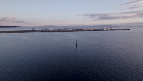 Tsawwassen-BC-ferries-terminal-port-in-Vancouver-Canada,-aerial-approach-harbour-with-boat-ready-to-sail-on-the-ocean-water-during-sunset