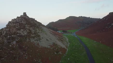 Absteigende-Luftaufnahme-Der-Dramatischen-Klippenspitze-Und-Der-Straße-Im-Valley-Of-Rocks-In-Exmoor,-Großbritannien-–-Drohnenaufnahme