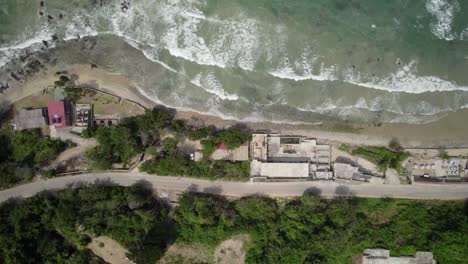 drone shot of road along the coast with caribbean houses and crashing waves