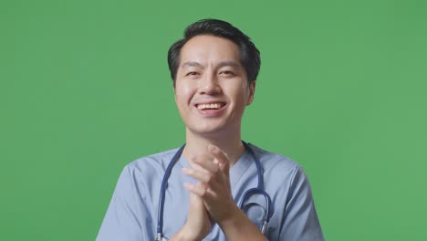 close up of asian male doctor with stethoscope clapping his hands on green screen background in the hospital