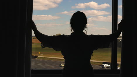 Aufnahme-Einer-Frau,-Die-Vorhänge-In-Einem-Hotelzimmer-öffnet,-Beginnend-In-Schwarz,-Um-Den-Blick-Aus-Dem-Fenster-Freizugeben