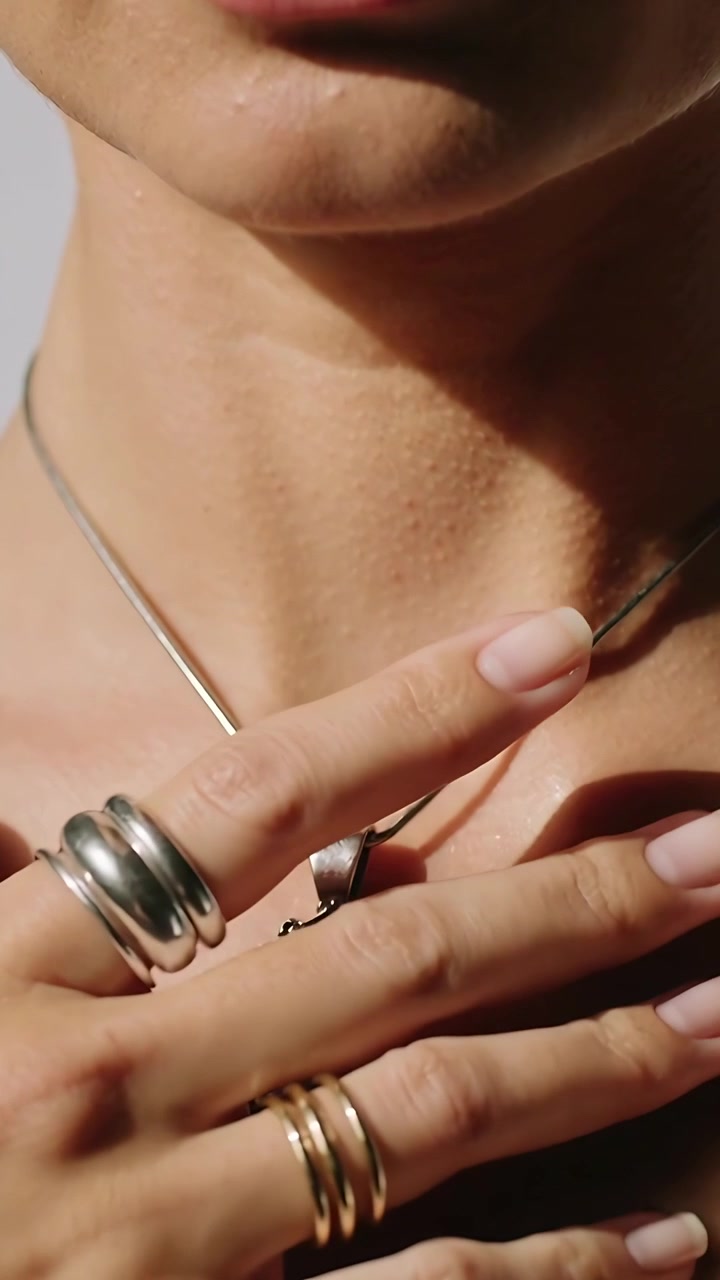 Video verticale: Donna che tiene una catena per il ciondolo, accarezza anelli e ciondolo, sistemandoli in studio.