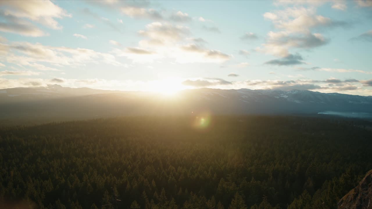 Smooth cinematic pan across a mountain valley at sunset, revealing snow-covered peaks, dramatic skies and a peaceful alpine landscape